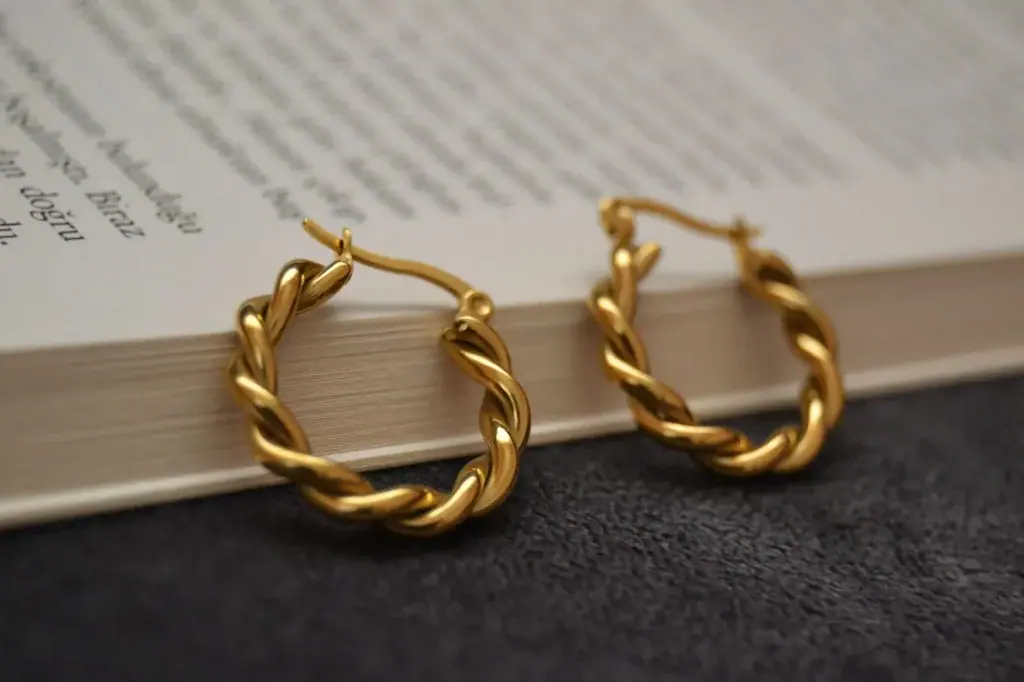 A pair of twisted gold hoop earrings resting on the pages of an open book.