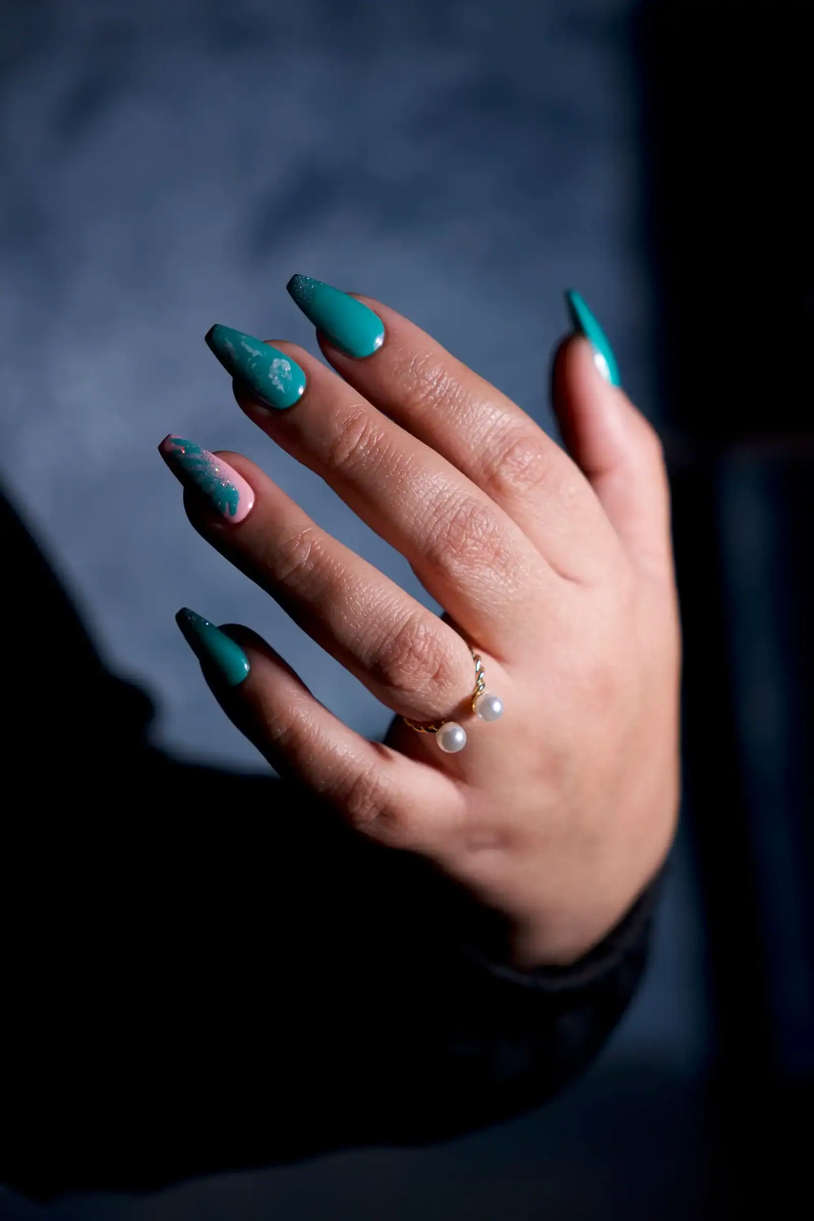 Long almond nails in glossy emerald green with a pearl ring