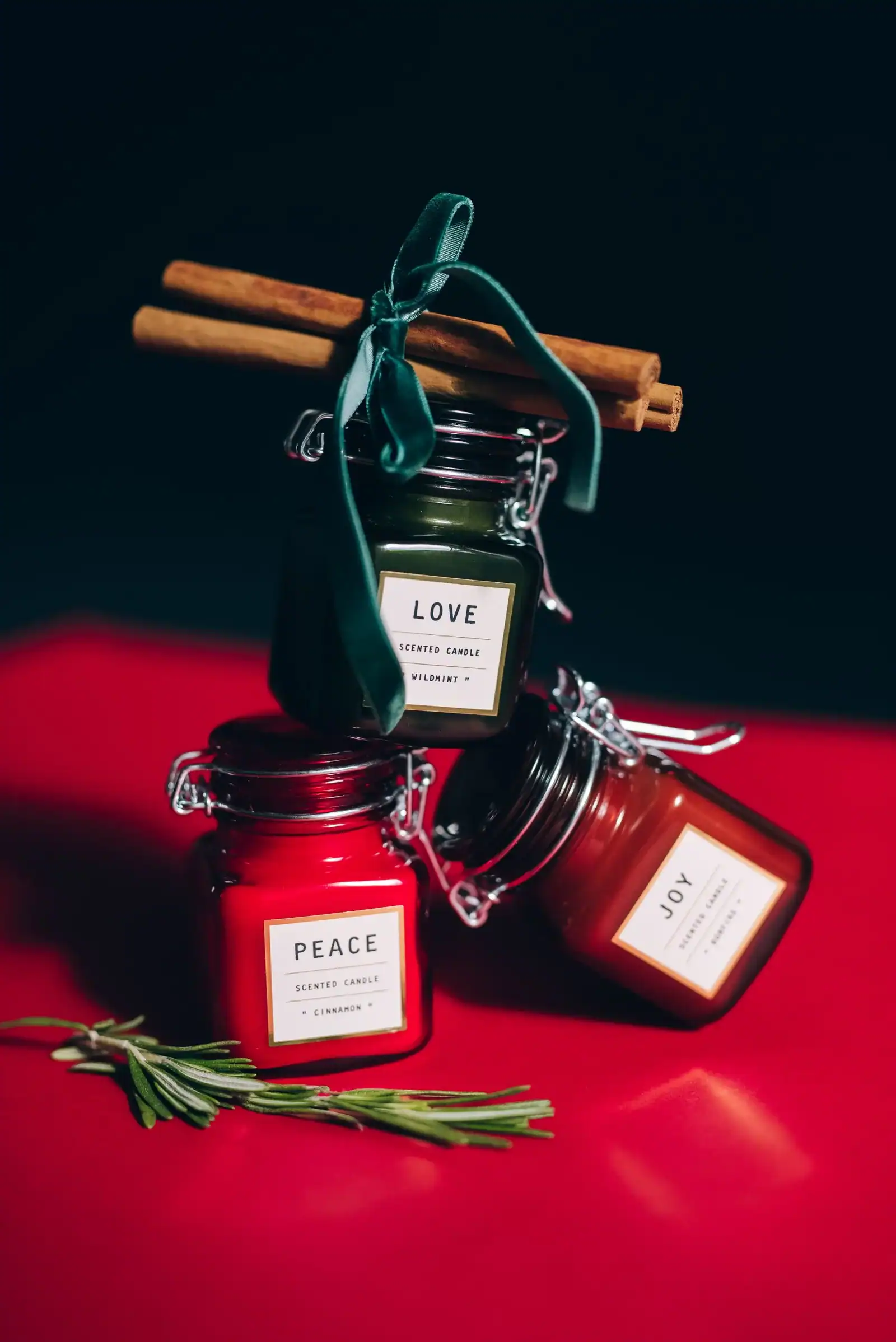 Red and green candles in jars with cinnamon sticks
