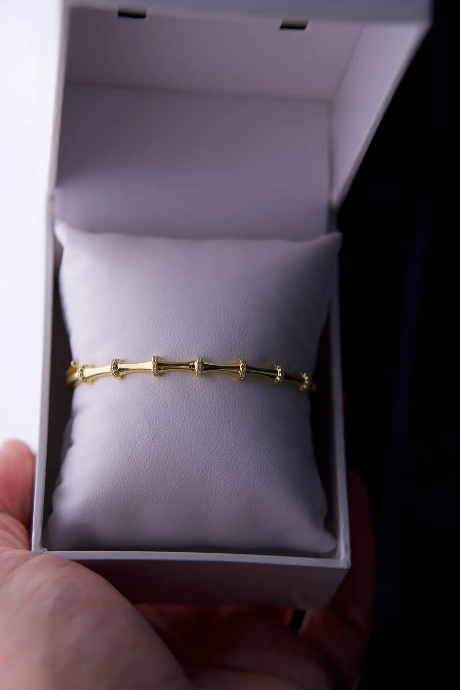 A gold bracelet in an open jewelry box