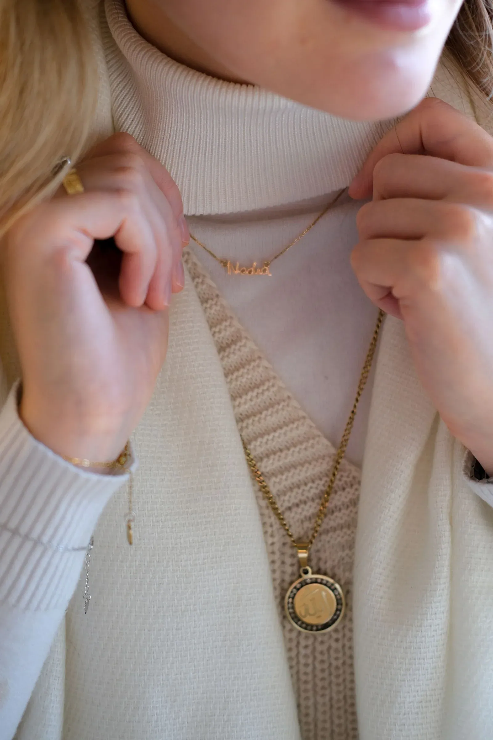 A woman wearing a layered gold necklace with a small pendant