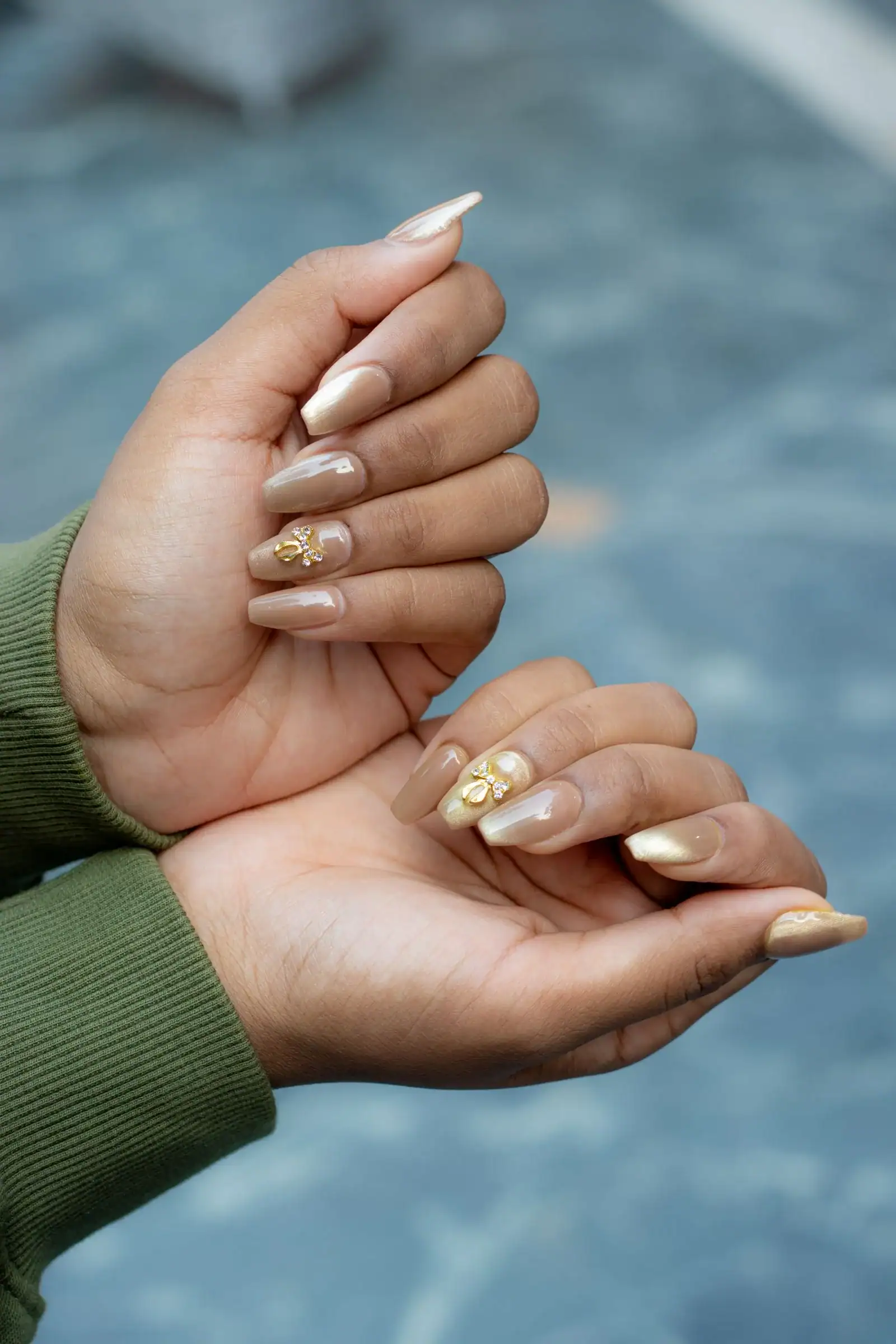 Nude almond nails with small gold foil flecks on a few nails