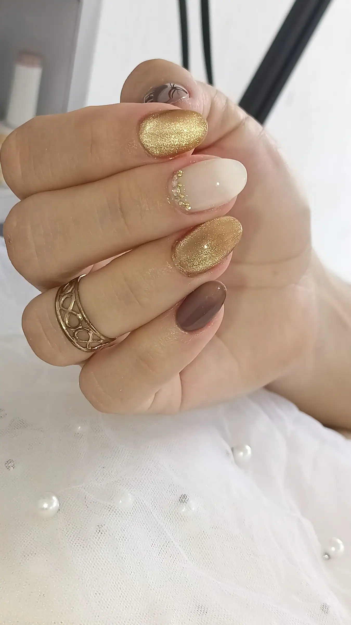 Milky white and gold glitter nails with one deep plum accent nail