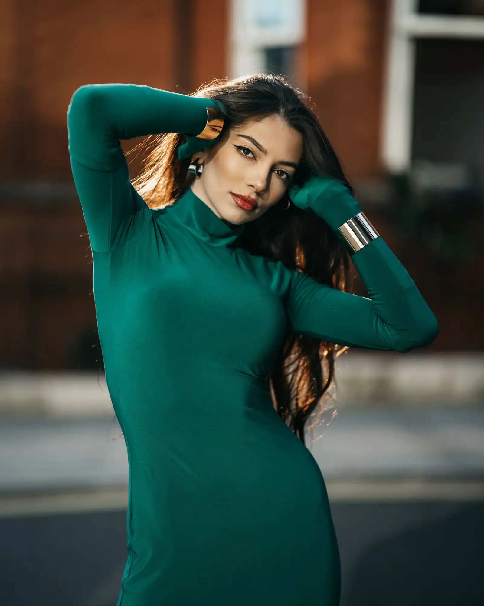 A woman in a long-sleeve emerald green fitted dress on a city street