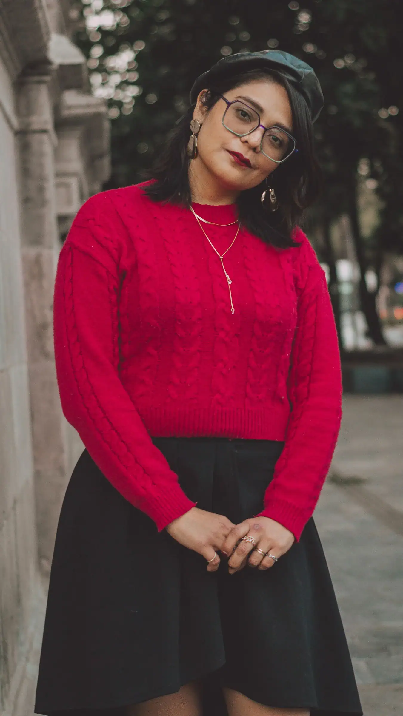 A woman in a red knit sweater and a black flared skirt