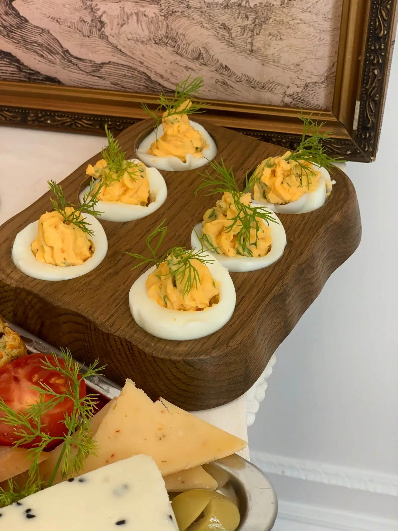 Deviled eggs topped with dill on a wooden serving board