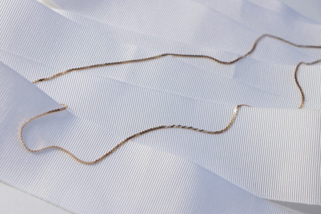 A fine gold chain lying on white fabric
