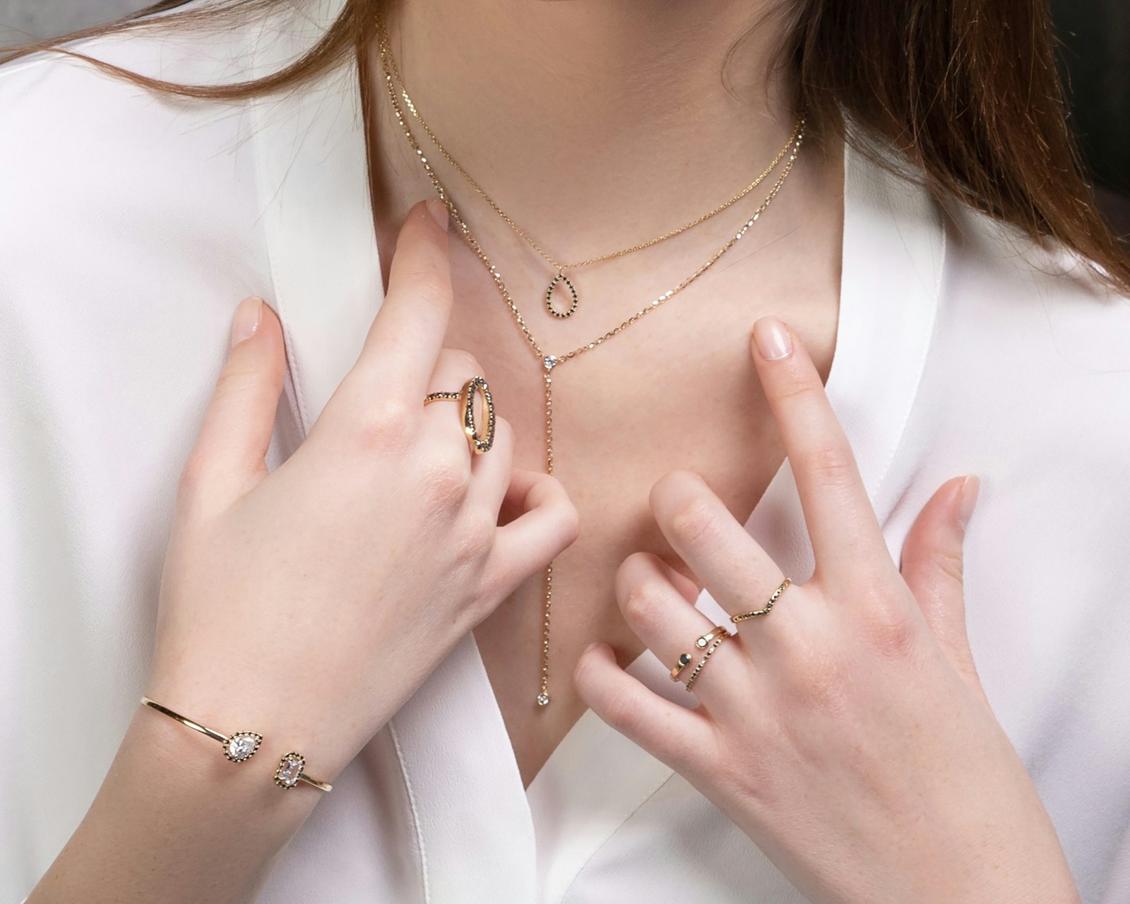 Woman wearing layered gold necklaces and stacked gold rings