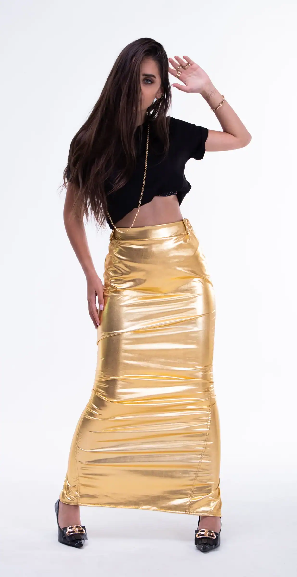 A woman in a long gold metallic skirt and a black crop top