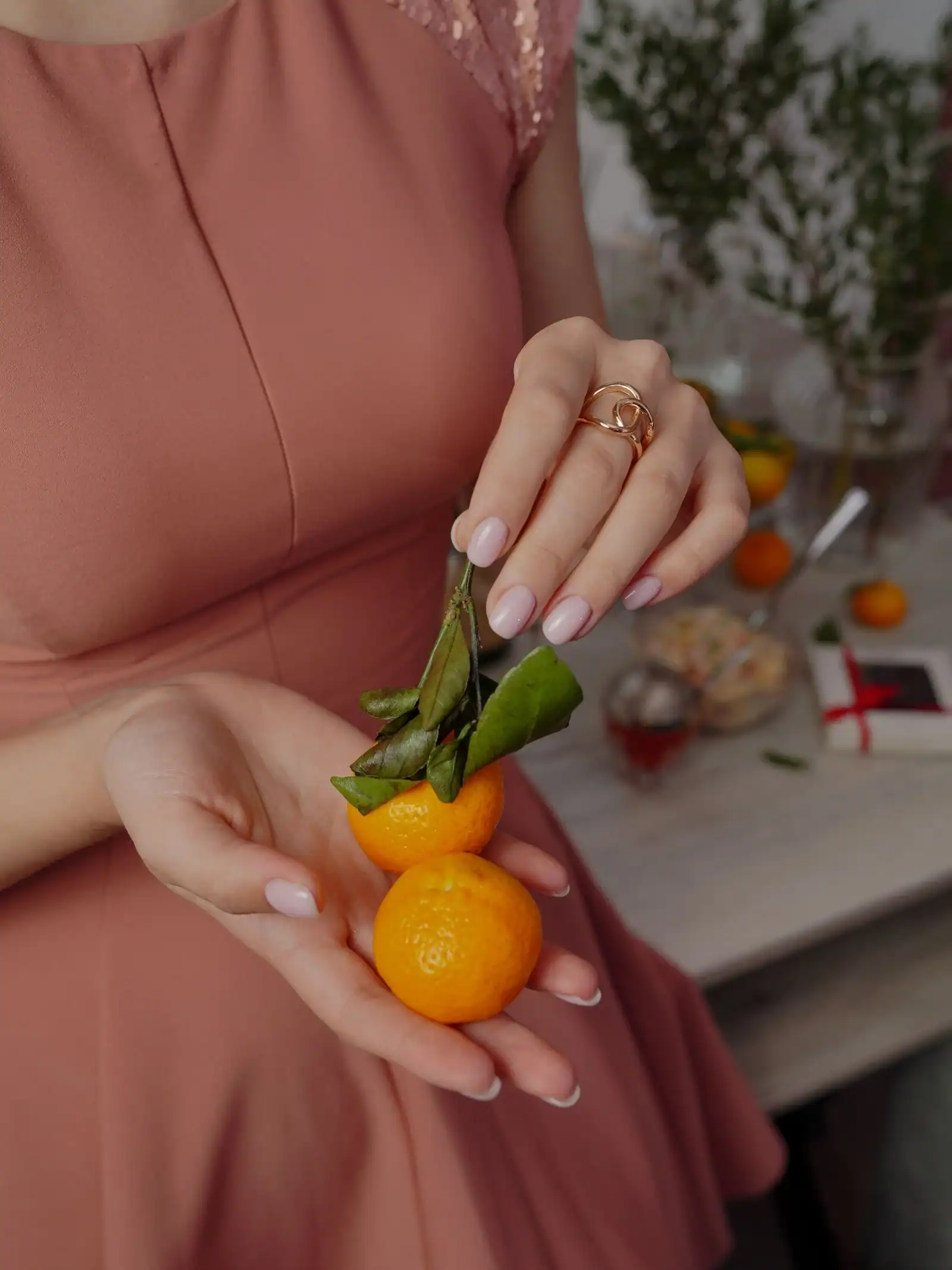 A hand with apricot nails holding a small orange