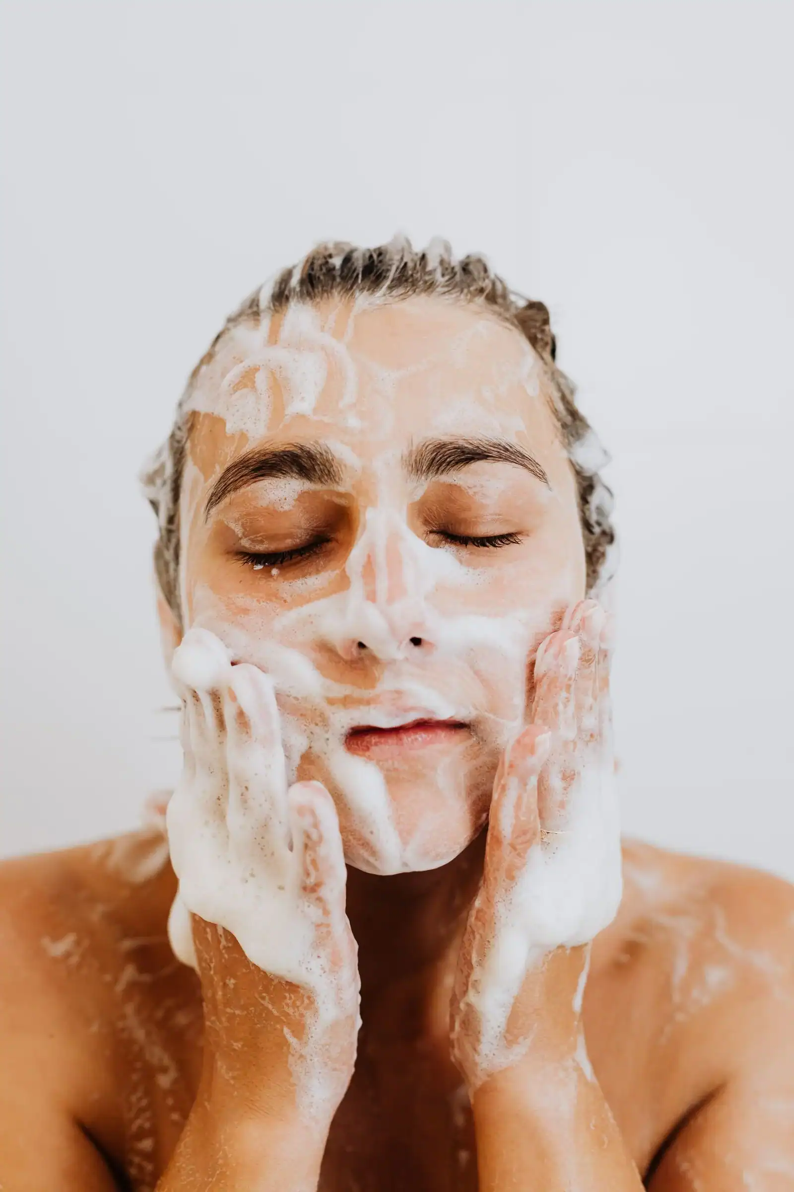 A person washing their face with cleanser lather