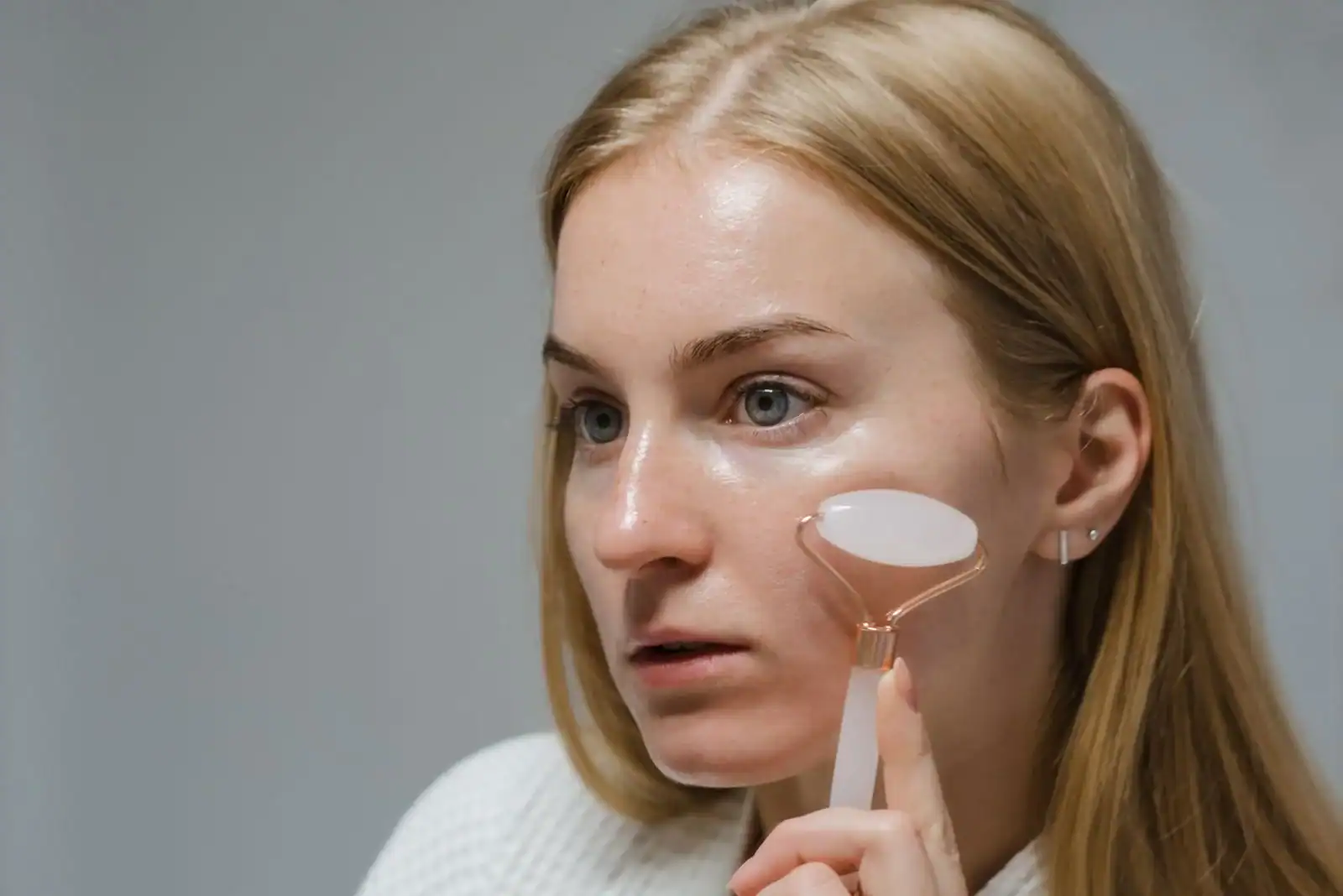 A woman using a rose quartz face roller