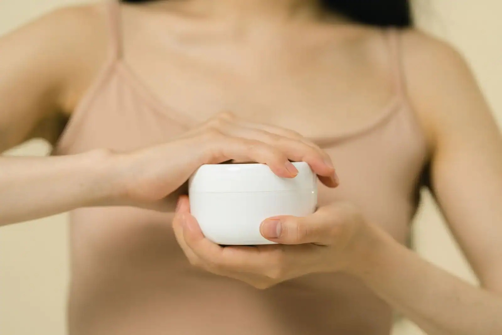 A woman holding a jar of moisturizer