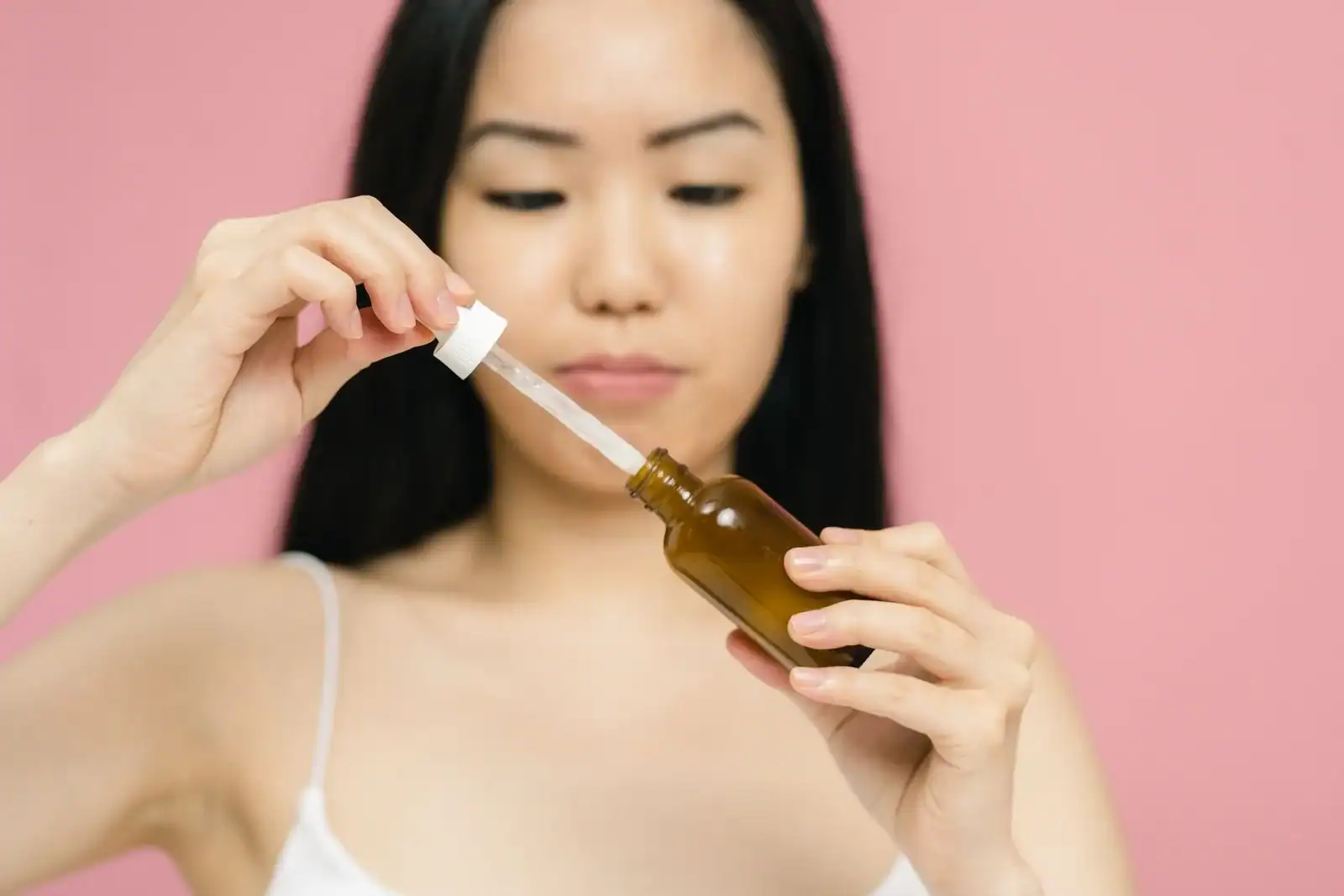 A woman holding a serum dropper bottle