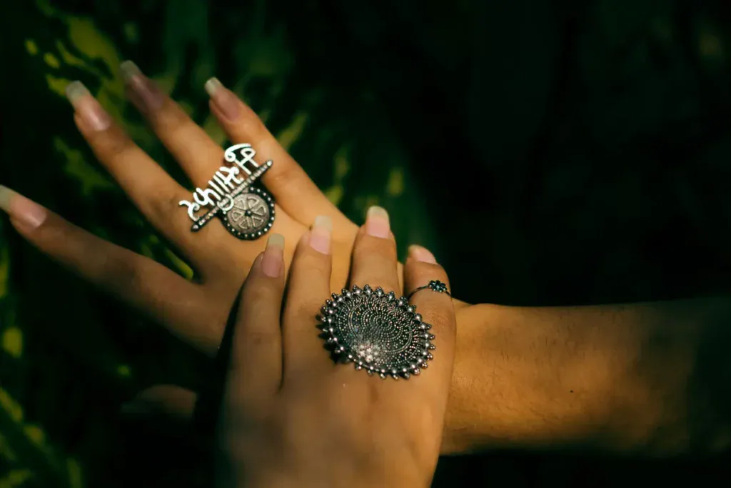 Hands wearing large silver rings with blackened, oxidized detailing.