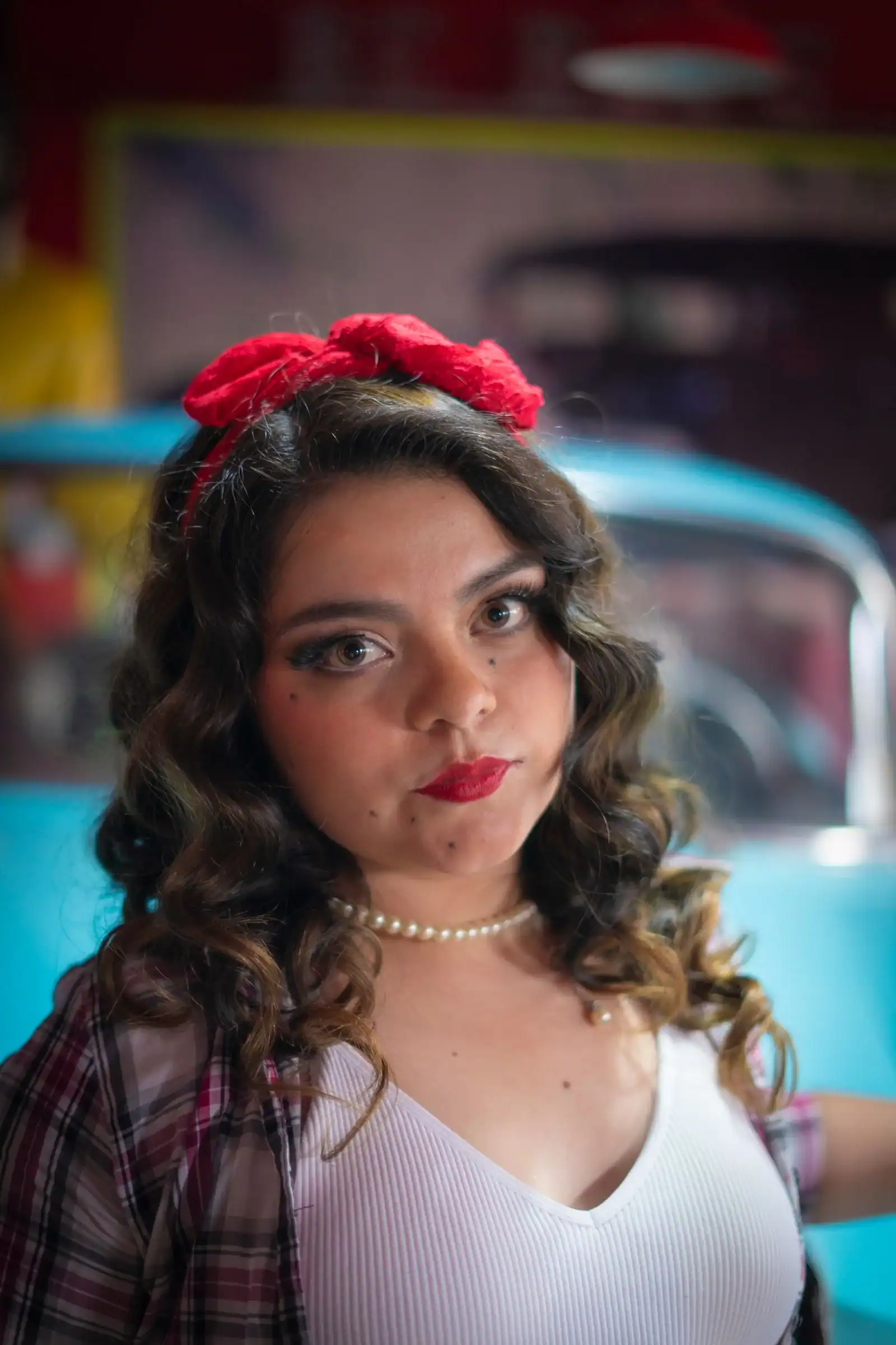 A woman with long curls and a red bow headband