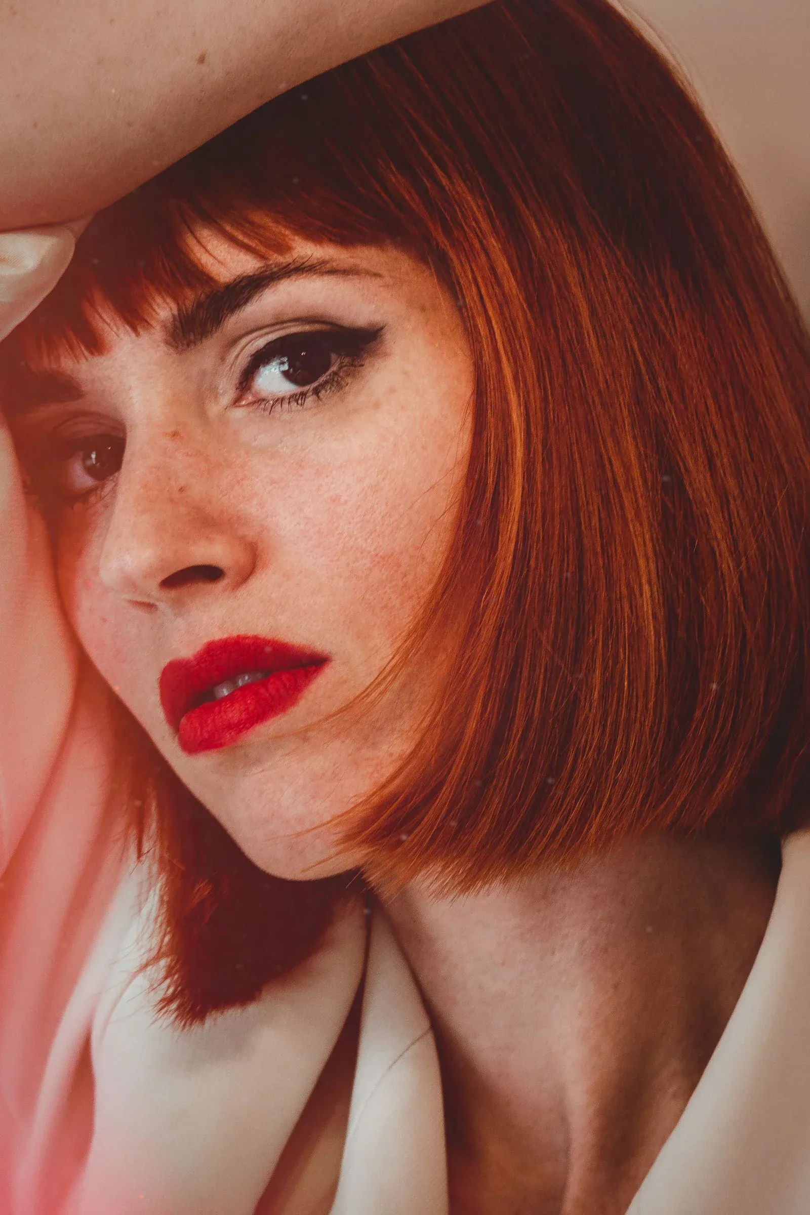 A woman with a copper bob, bangs and red lipstick