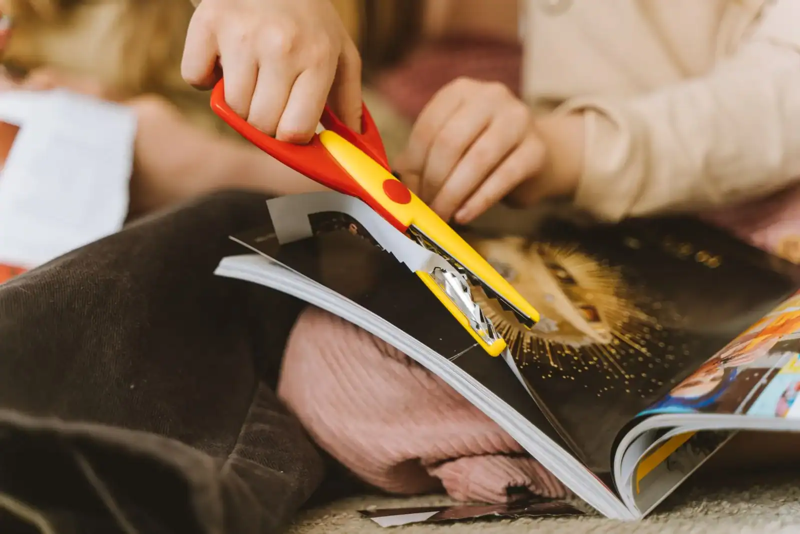 Hands cutting pictures out of a magazine with scissors