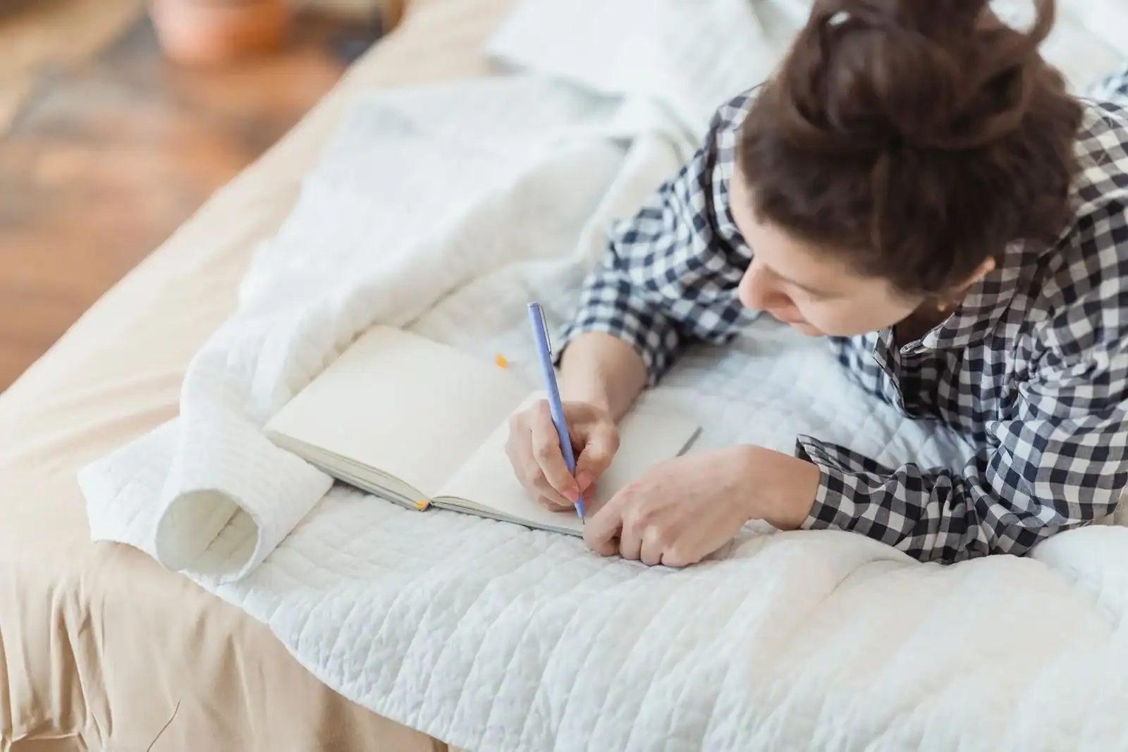 A woman writing in a journal on a bed