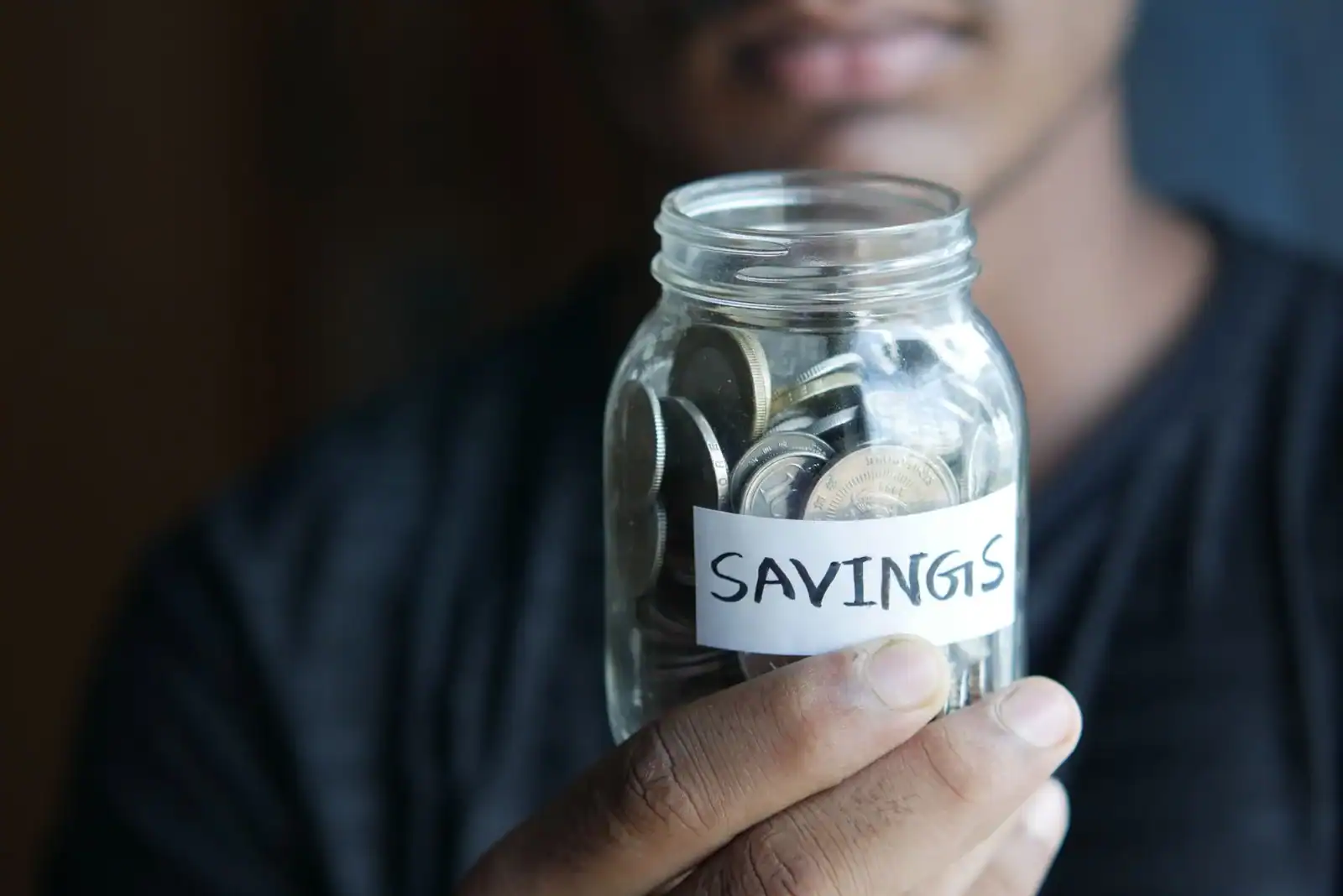 A person holding a savings jar of coins