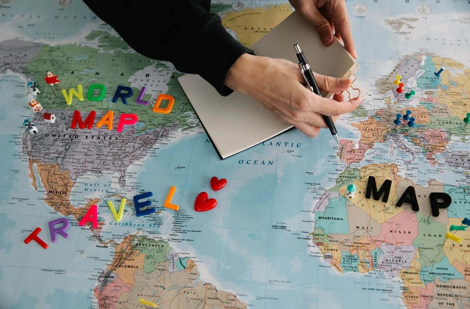 A hand planning a trip on a world map