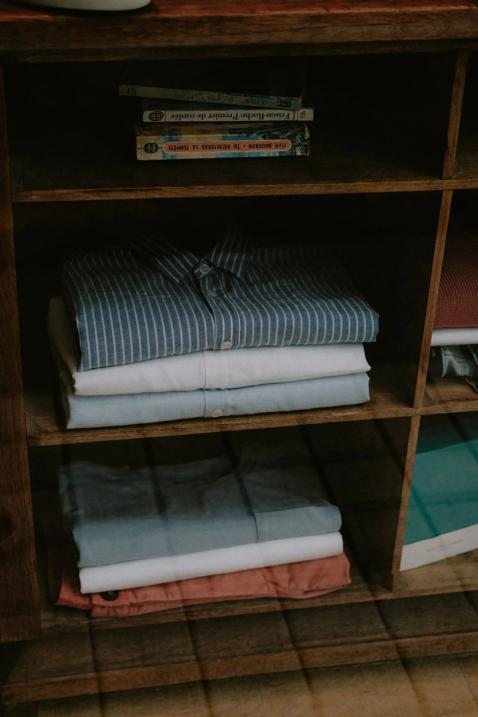 Folded denim and shirts on a wooden shelf