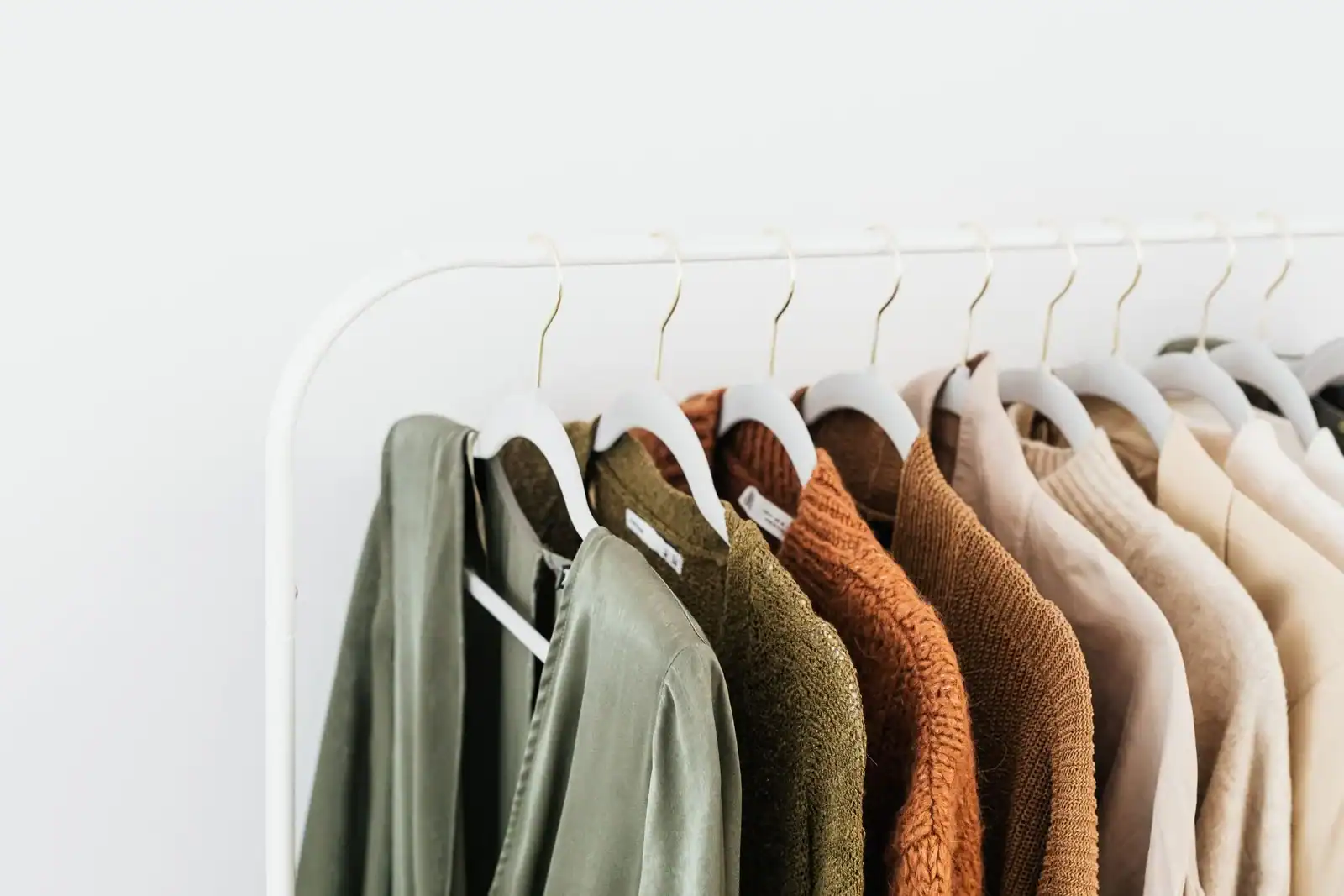 A rail of neutral jackets and shirts in green, rust and cream