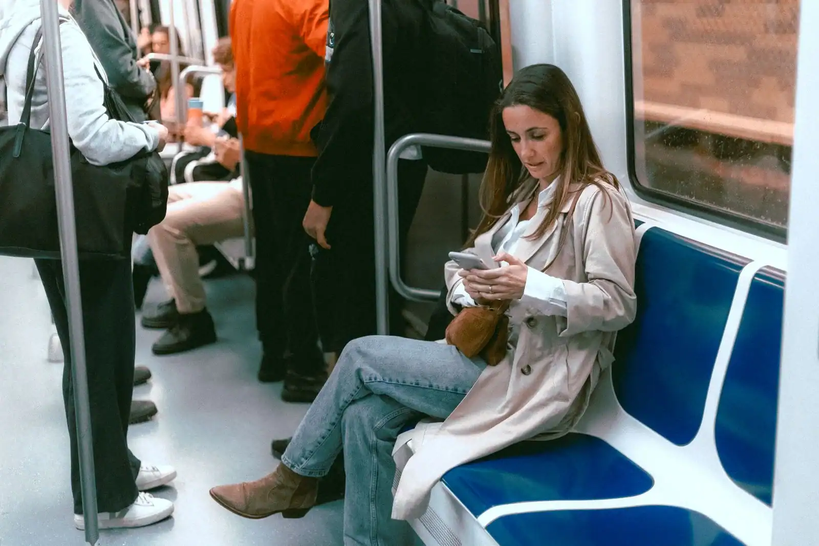 A woman in a long beige trench coat on a train